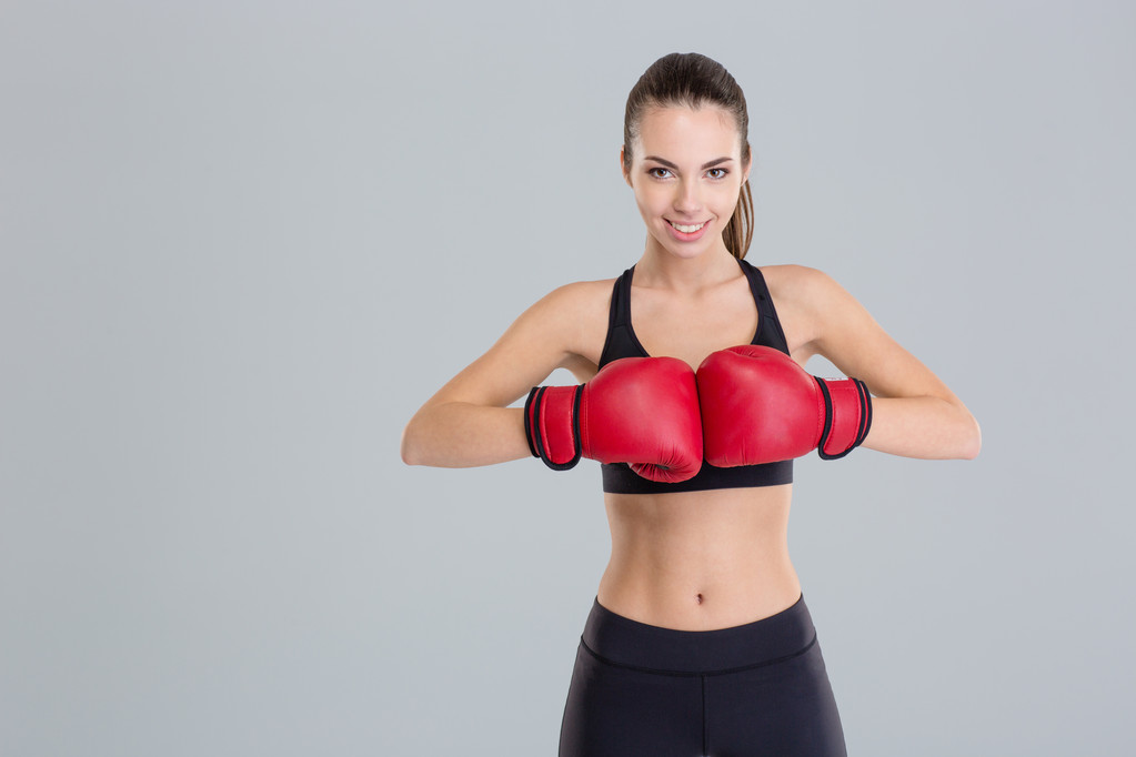 Mooie lachende jonge fitness vrouw draagt rode bokshandschoenen  - Foto, afbeelding