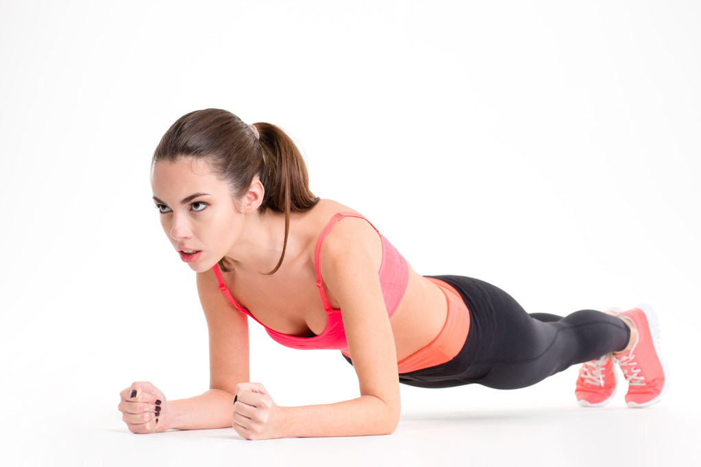 Geconcentreerde mooie fitness meisje in sportwear uitoefening doen plank  - Foto, afbeelding