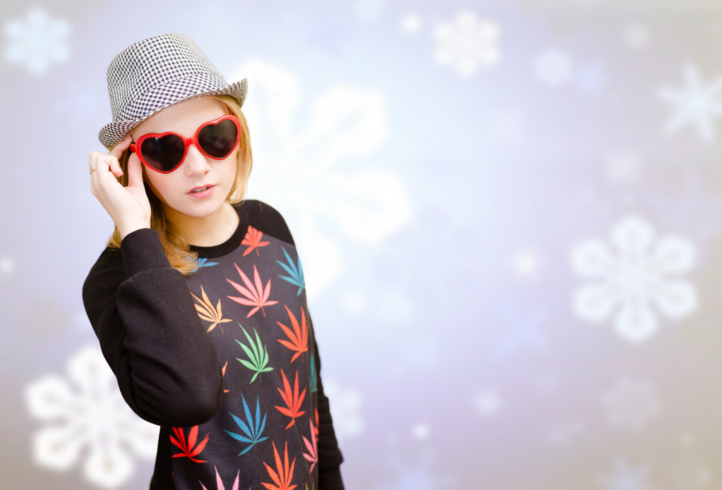 Beautiful woman in fancy sunglasses smiling on snowflakes blurred background - 写真・画像