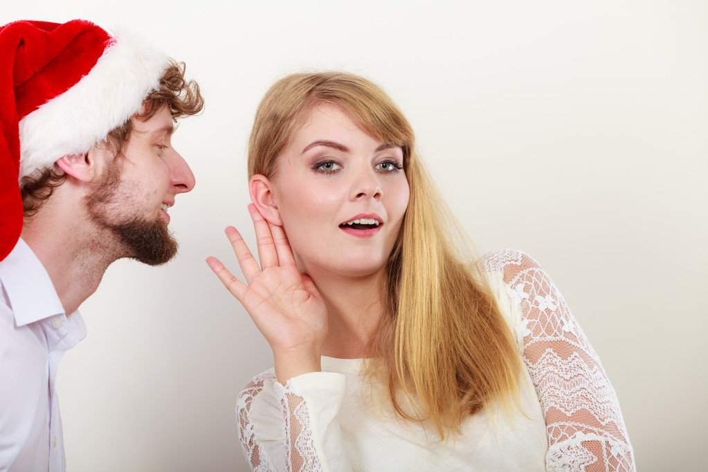 Man in santa hat fluisteren aan vrouw oor. - Foto, afbeelding