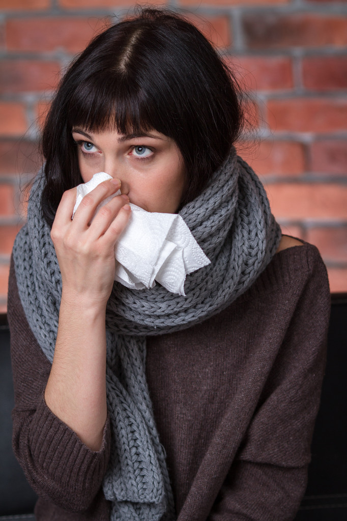 Young sick woman sitting in scarf and sweater with handkerchief - Fotó, kép