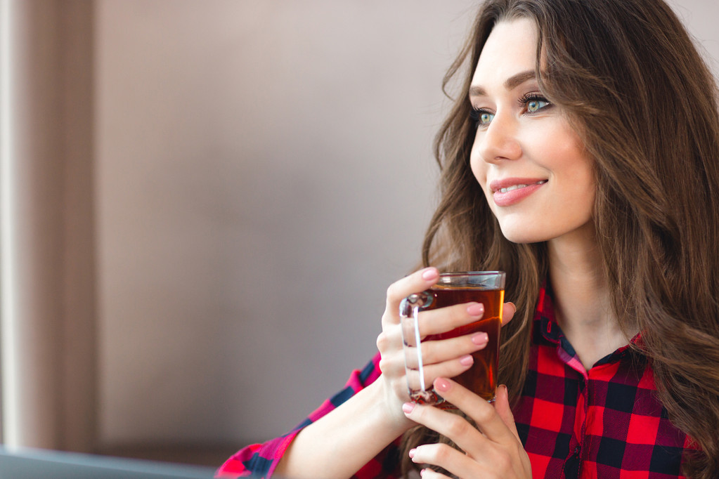 Femme heureuse réfléchie tenant un verre avec du thé
 - Photo, image
