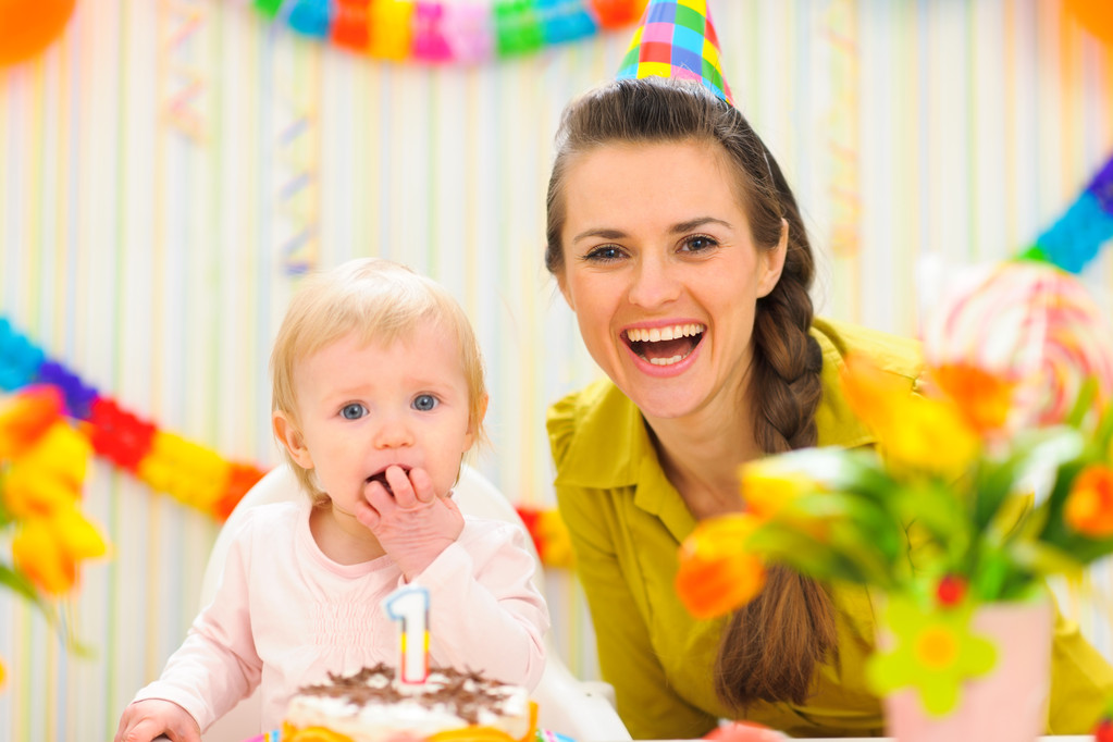 誕生日ケーキを食べる赤ちゃんを持つ母親の肖像画 - 写真・画像