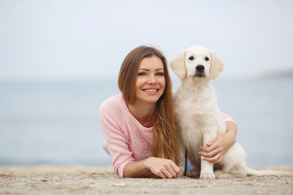 A young woman near the sea with a puppy Retriever - Zdjęcie, obraz