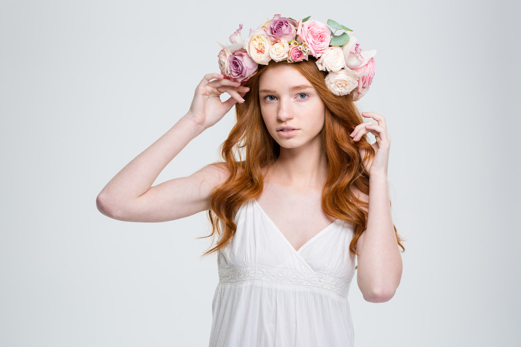 Όμορφη νεαρή γυναίκα με σγουρά μαλλιά κόκκινο στα λουλουδιών στεφάνι  - Φωτογραφία, εικόνα