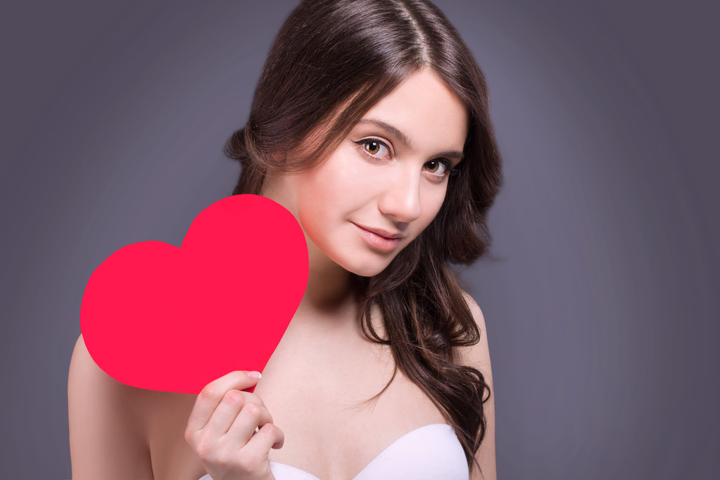 Portrait of Beautiful gorgeous smiling woman with glamour bright makeup and red heart in hand. Valentine's Day. Beautiful smiling woman with a gift in the form of two heart in his hands. - Photo, Image