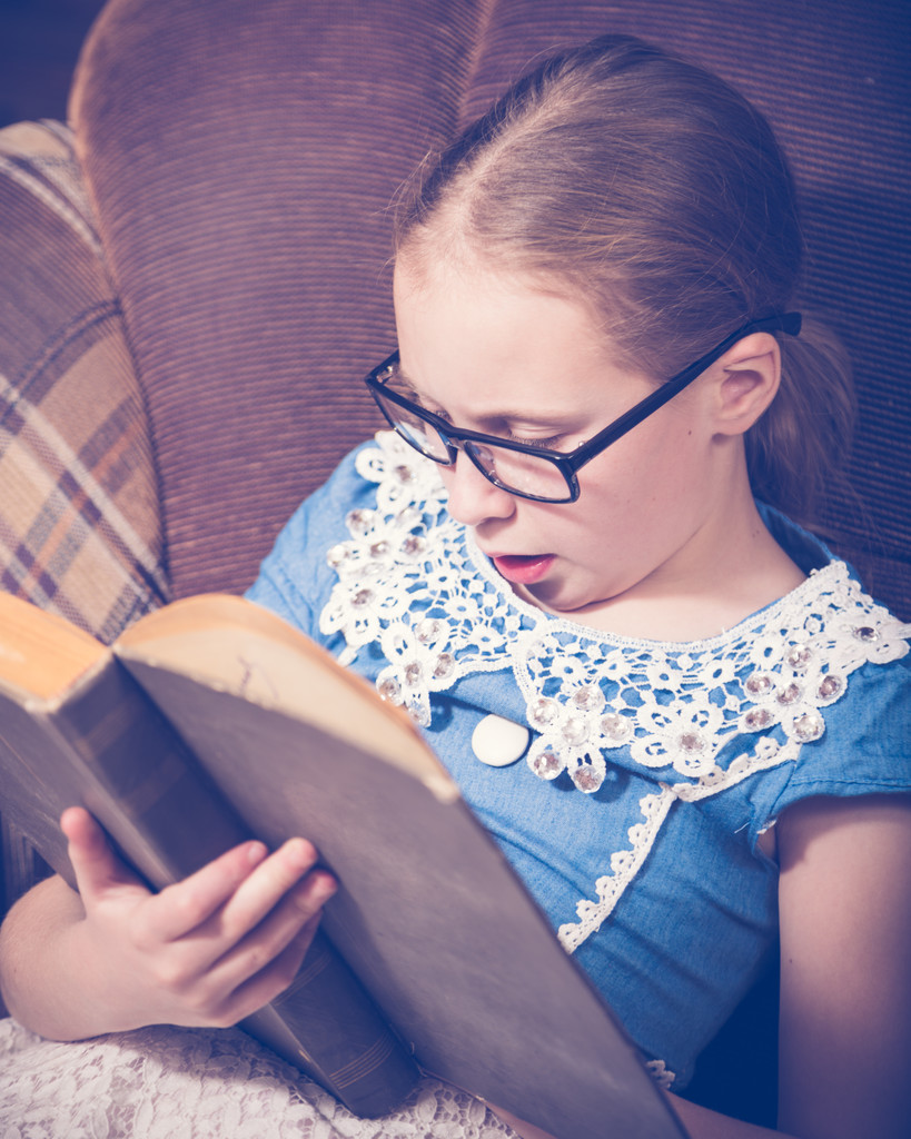 家で本を読んでいる女の子は肘掛け椅子に座ってください。. - 写真・画像
