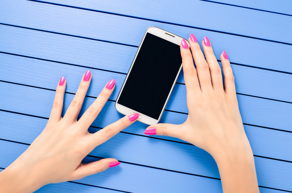 Mano femminile utilizzando il telefono cellulare su tavolo di legno blu
 - Foto, immagini