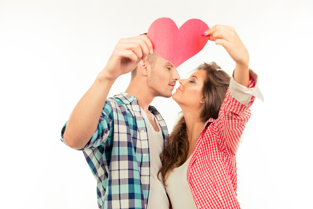 Cheerful cute couple in love holding paper heart and kissing - Photo, Image