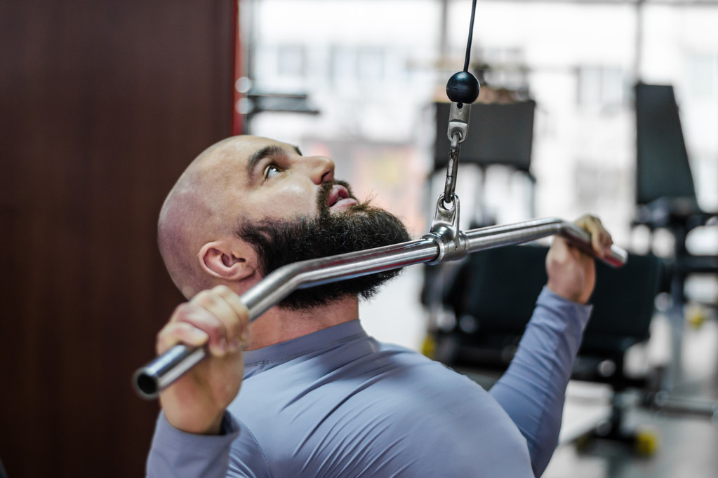 Αρσενικό αθλητής κάνει ασκήσεις σε pulldown μηχάνημα στο γυμναστήριο, υγιεινό τρόπο ζωής - Φωτογραφία, εικόνα