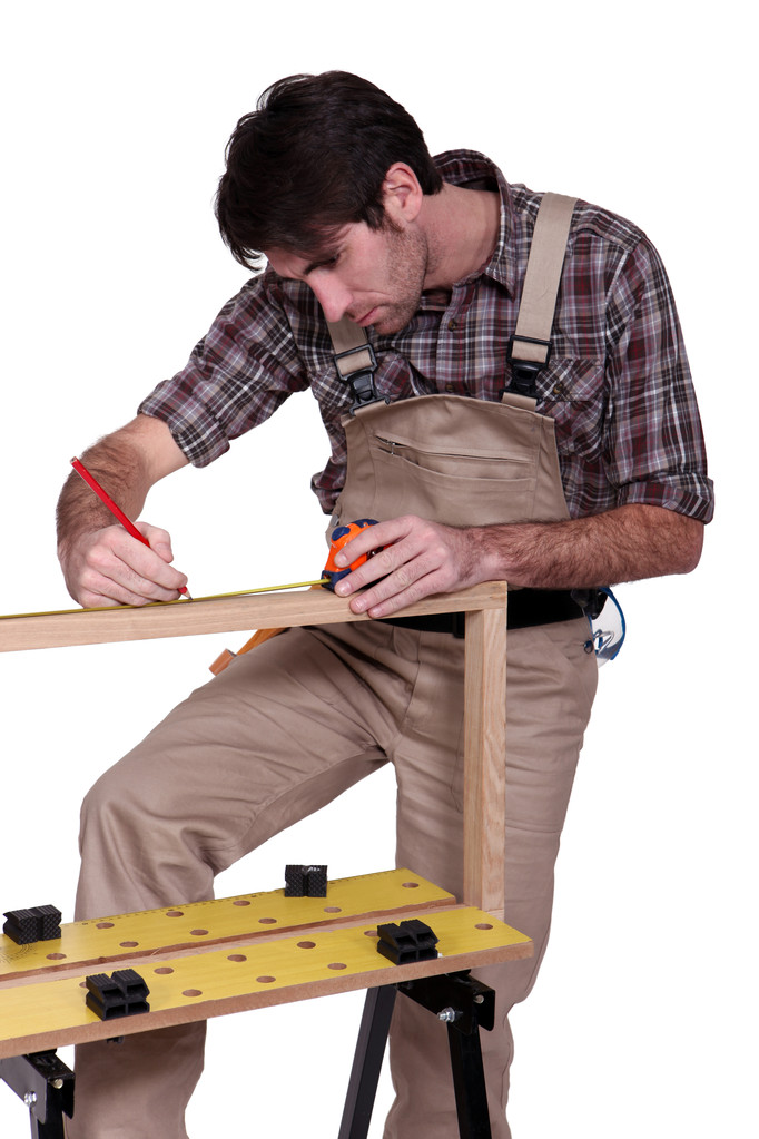 Человек измеряет деревянную раму
 - Фото, изображение