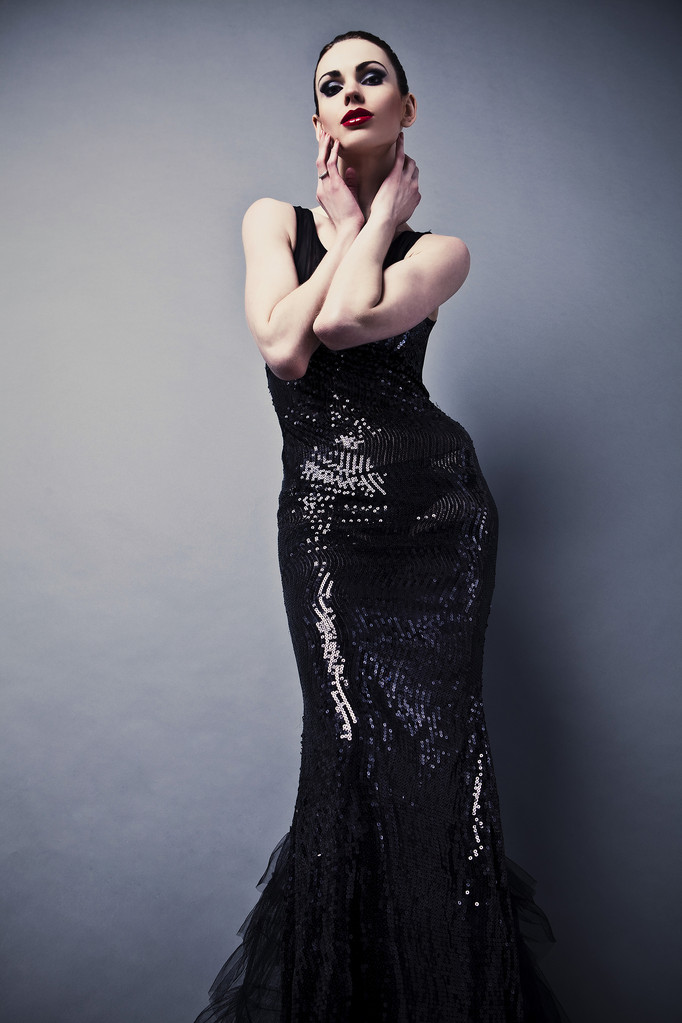 Красива жінка на чорній класичній сукні позує в студії
. - Фото, зображення