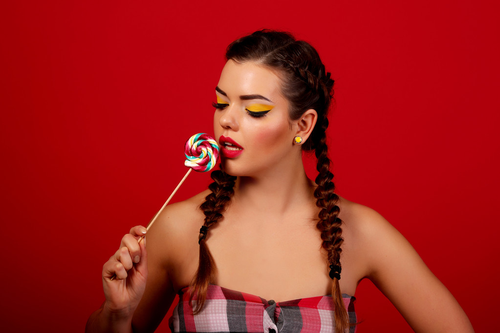 hermosa chica no fondo rojo, sosteniendo un caramelo
 - Foto, imagen