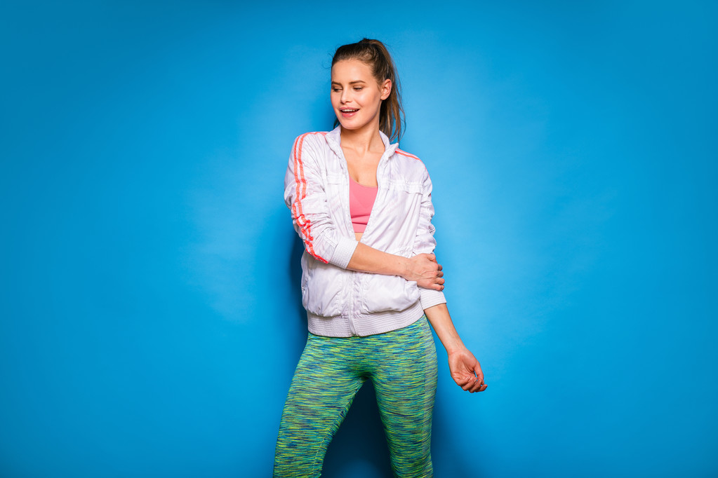 young athletic woman in hoodie on blue background - Photo, Image