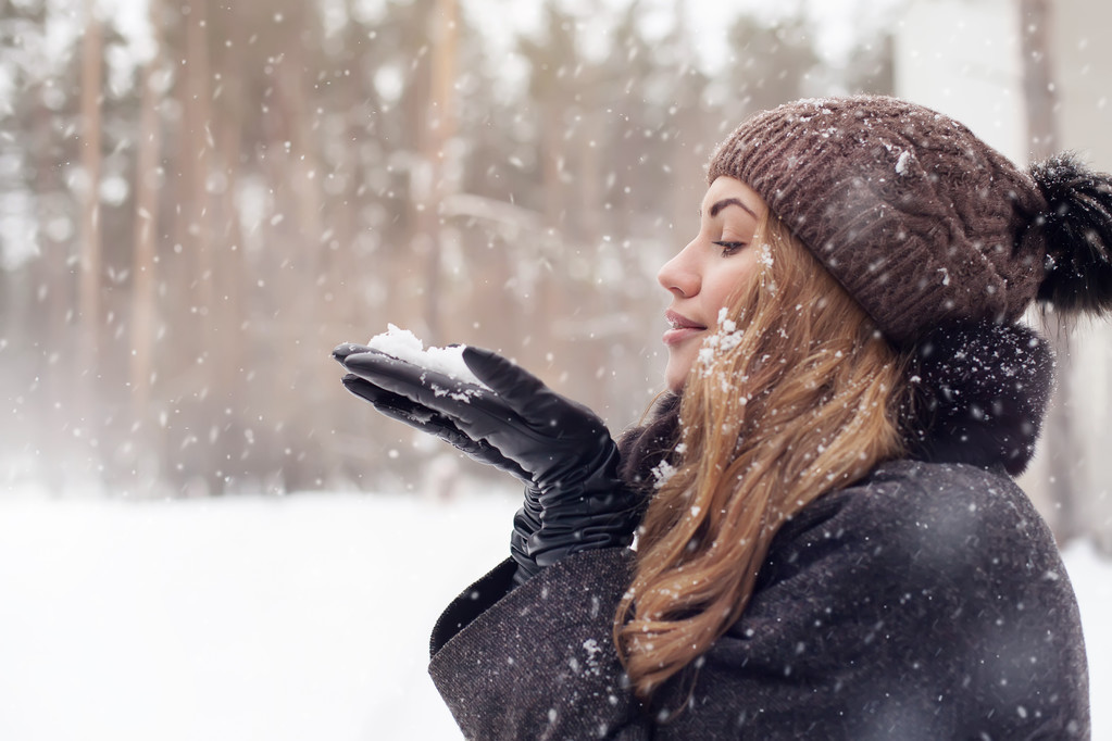 Портрет девушки на улице. Зимняя женщина выдувает снег в парке, крупным планом
 - Фото, изображение