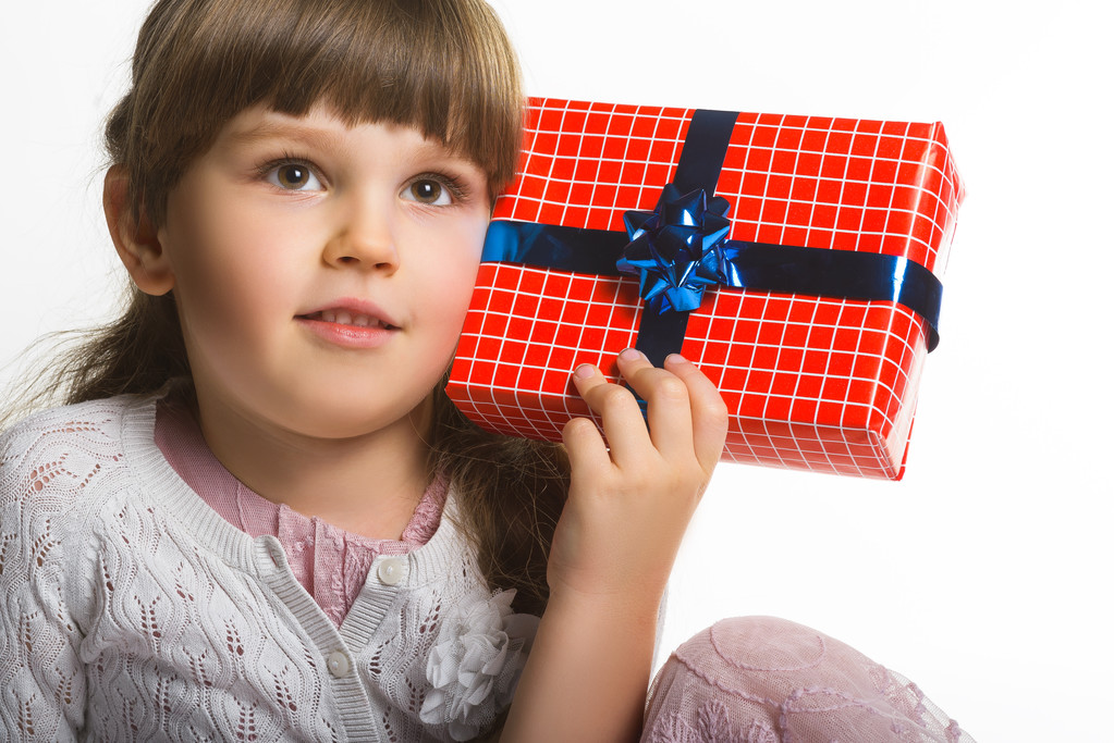 Onnellinen pieni tyttö laittaa lahjapakkauksen korvaan eristetty valkoisella taustalla
 - Valokuva, kuva