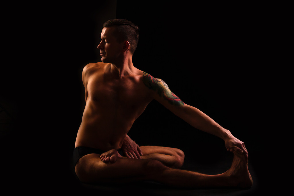 mladý muž dělá jógu a gymnastiku, kroucené, polovičním lotosu - Fotografie, Obrázek