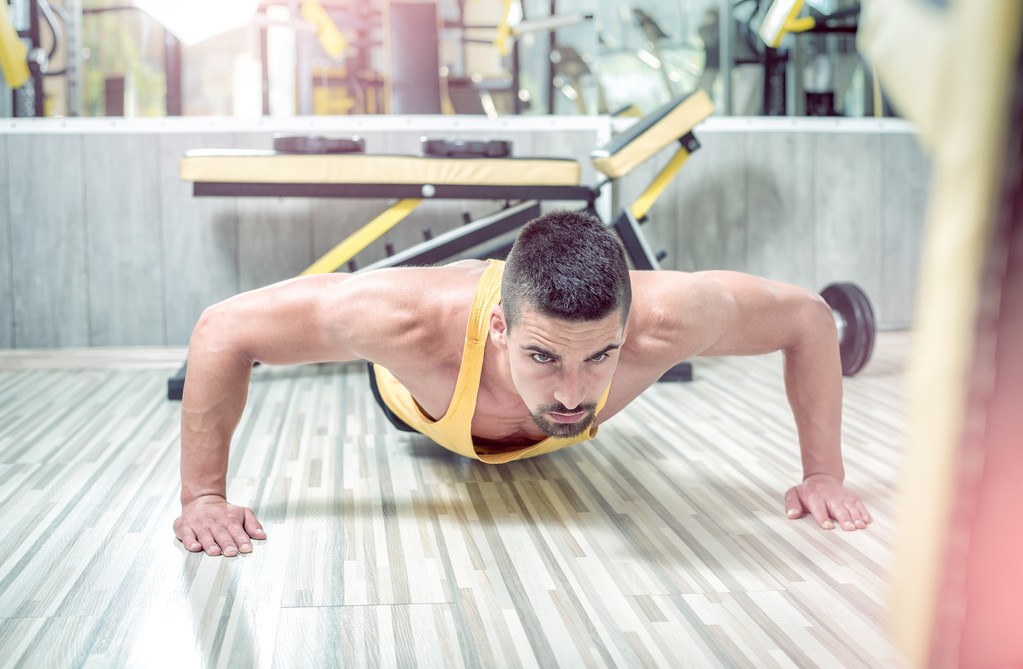 Νεαρός άνδρας κάνει push-ups στο γυμναστήριο - Φωτογραφία, εικόνα