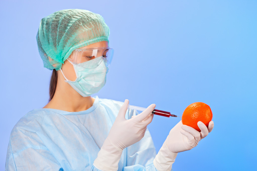 młoda kobieta lekarz wstrzykiwanie owoc pomarańczowy ze strzykawki na niebiesko - Zdjęcie, obraz
