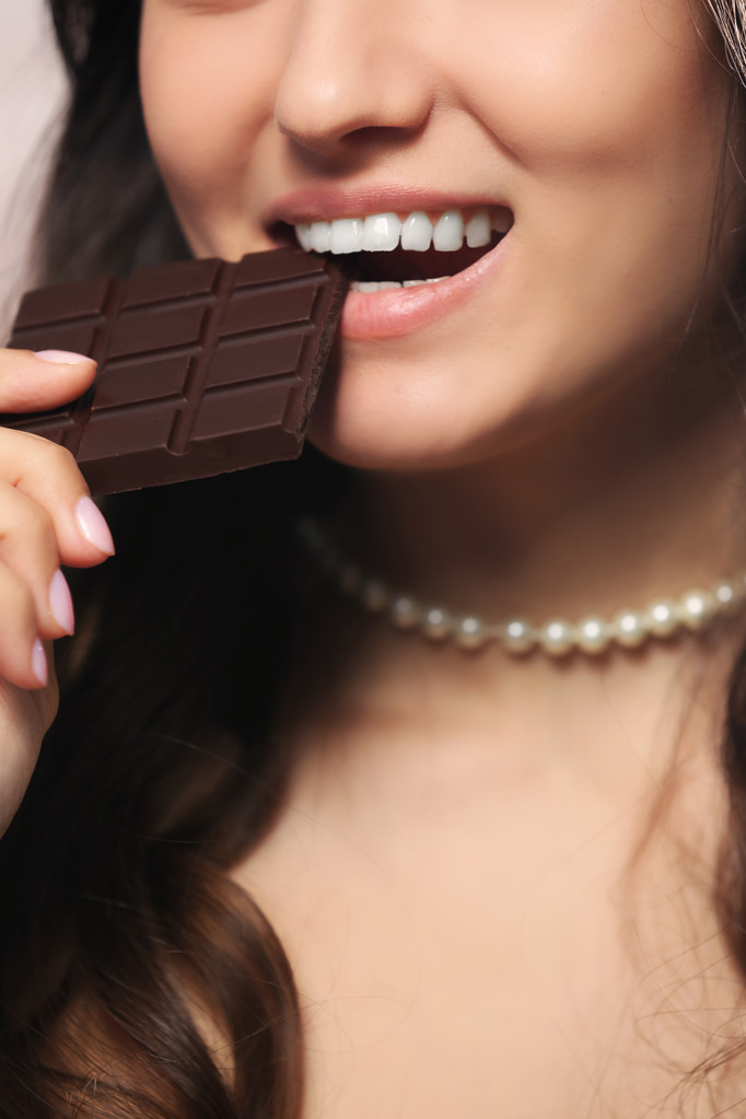 Chocolade liefhebbende vrouw beten bar om te genieten van de smaak, close-up - Foto, afbeelding
