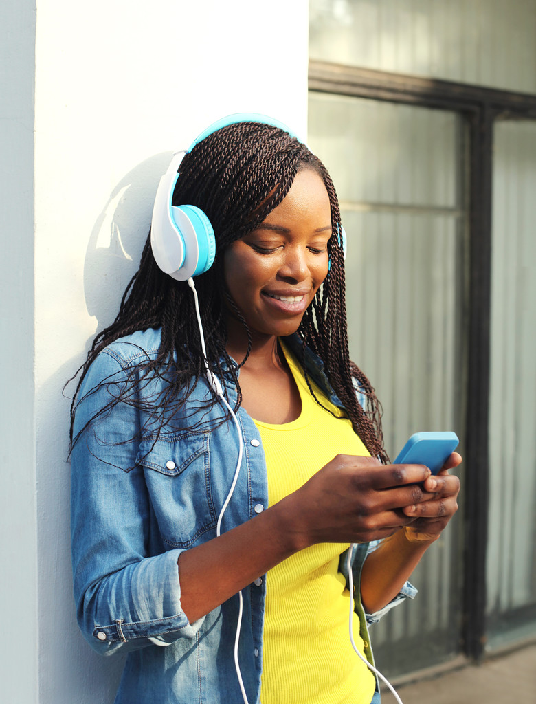 Kaunis hymyilevä afrikkalainen nainen kuulokkeilla kuuntelee musiikkia
 - Valokuva, kuva