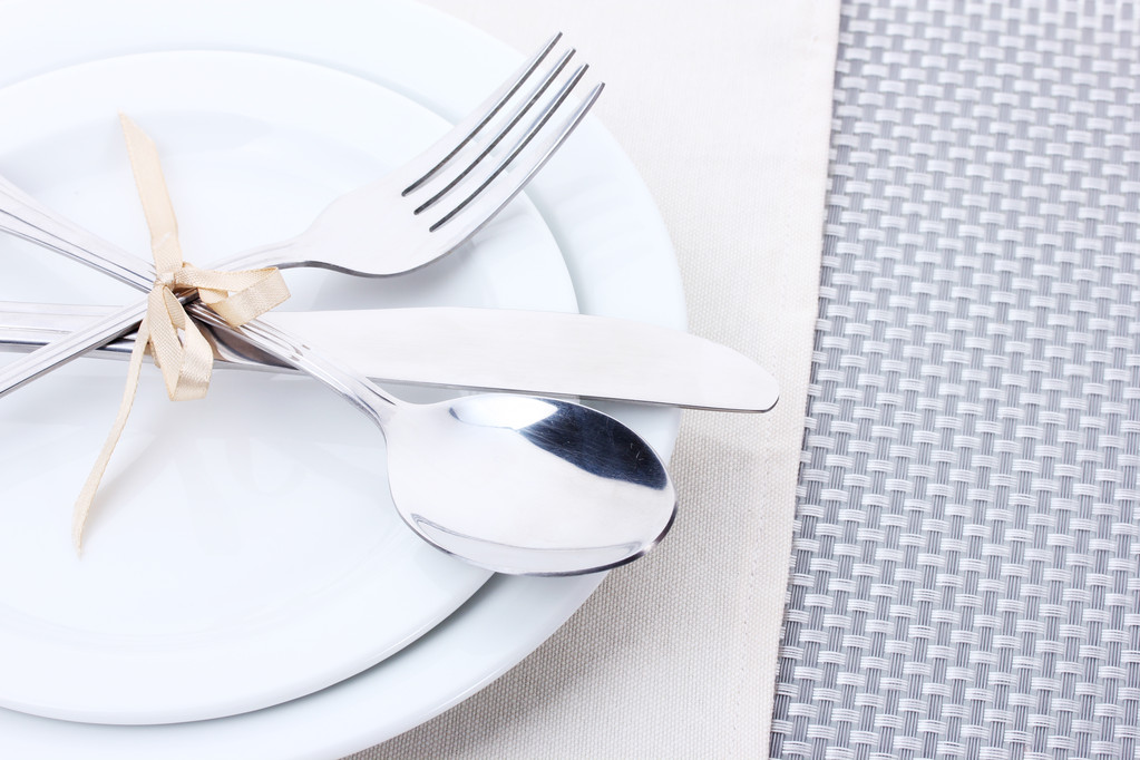 beyaz boş tabak çatal, kaşık ve bıçak ile bir şerit üzerinde gri bir masa örtüsü ile bağlıdır. - Fotoğraf, Görsel
