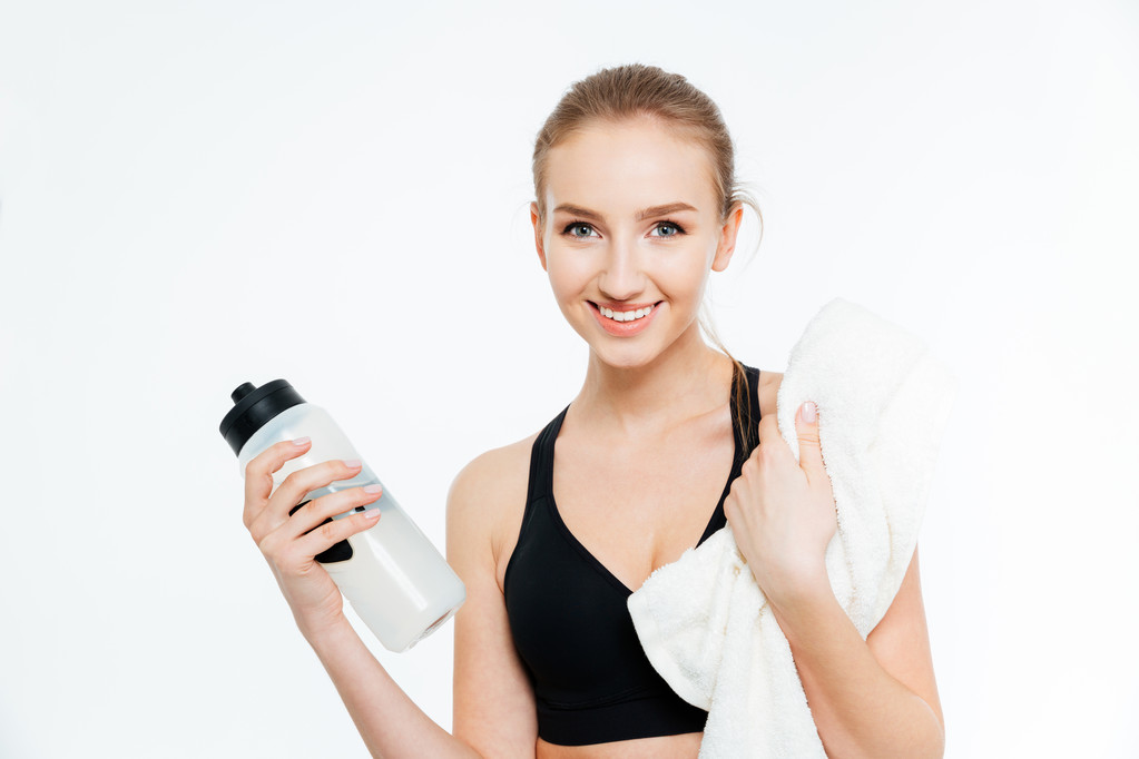 Mujer alegre atleta bebiendo agua y sosteniendo toalla blanca
  - Foto, imagen