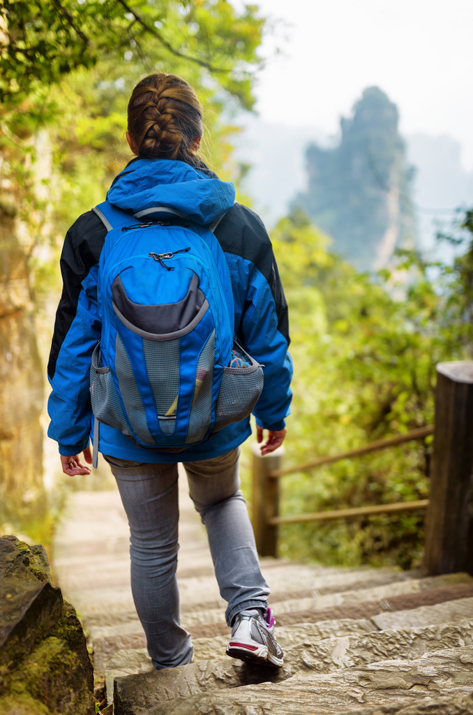 Joven turista femenina con mochila azul descendiendo escaleras de piedra
 - Foto, imagen
