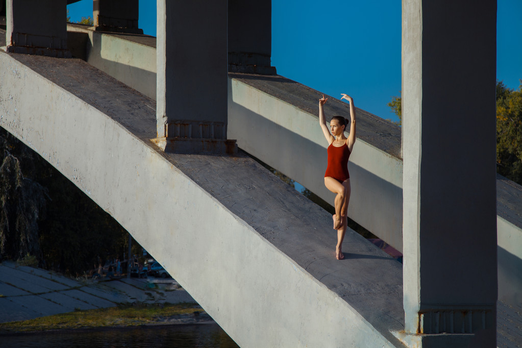 Молода красива жінка гімнастка позує на мостовому поясі
 - Фото, зображення