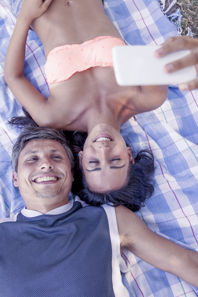 jovem casal deitado em pano tomar uma selfie deitado no parque
 - Foto, Imagem