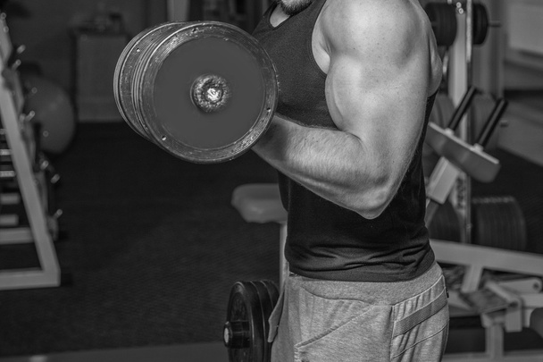 Man at the gym. Man makes exercises with barbell. Sport, power, dumbbells, tension, exercise - the concept of a healthy lifestyle. Article about fitness and sports. - Fotoğraf, Görsel