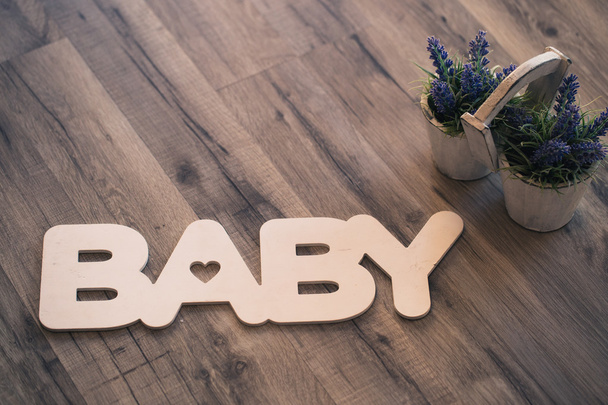 Слово baby деревянными буквами на полу с горшком лаванды
 - Фото, изображение