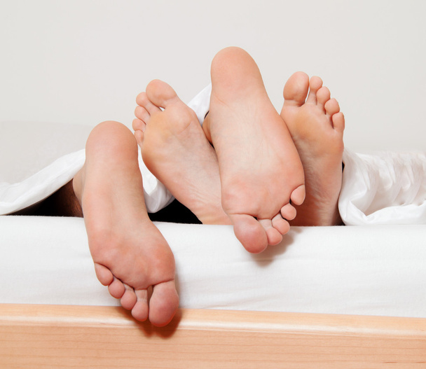 Feet of a couple in bed. - Фото, зображення