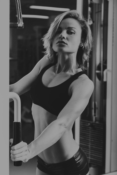 Σπορ γυναίκα στο γυμναστήριο. Όμορφη μυϊκή ταιριάζει γυναίκα άσκησης τους μυς κτίριο. Ωραίο σέξι γυναίκα κάνει προπόνηση στο γυμναστήριο. - Φωτογραφία, εικόνα