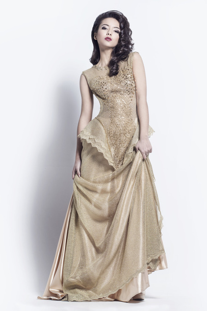 Beautiful woman dressed in golden dress - Fotó, kép