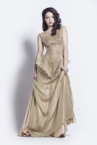 Beautiful woman dressed in golden dress - Fotoğraf, Görsel