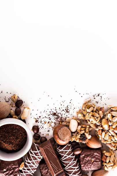 Roasted coffee beans, chocolate, candy, nuts, cup and the place for inscriptions on white background - Photo, Image
