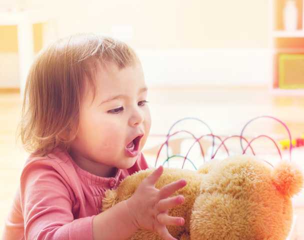 toddler girl playing with her teddy bear - Foto, afbeelding