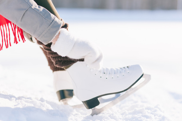 Girl in dress skates mittens tying shoelaces - Fotografie, Obrázek