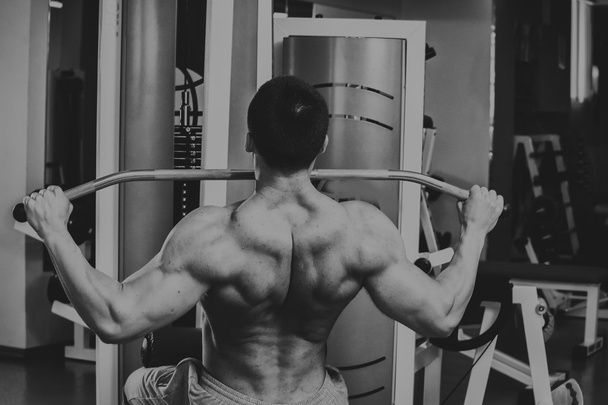 Homem musculoso forte fazendo exercícios no ginásio. Corpo bonito em uma foto em preto e branco. Estilo de vida saudável
. - Foto, Imagem