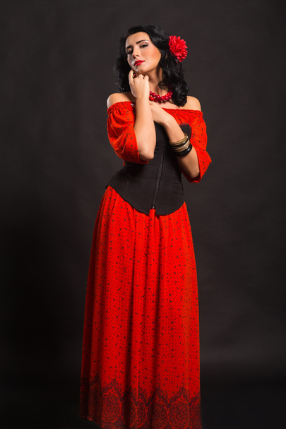 Портрет красивой молодой женщины в красно-черном платье на темном фоне
. - Фото, изображение