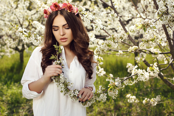 gorgeous sensual woman with dark hair in elegant dress posing in blossom garden - Foto, Imagem