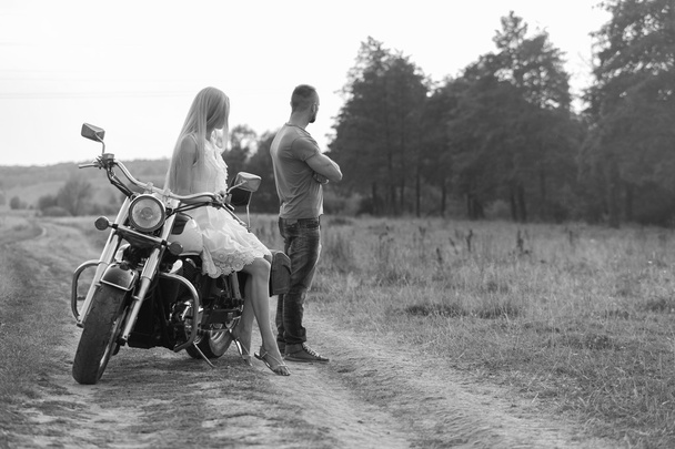 Schwarz-Weiß-Foto-Biker-Paar auf einem Motorrad im Feld. - Foto, Bild