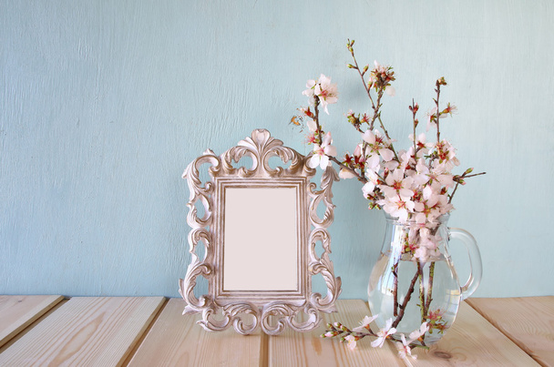 vintage blank frame next to white spring flowers. selective focus. template, ready to put photography - Fotó, kép