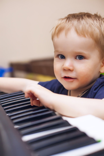 Маленький мальчик любит играть на электрическом пианино (синтезатор
)  - Фото, изображение