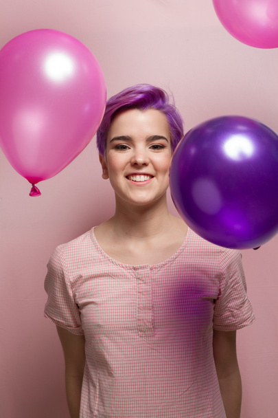 Mulher violeta de cabelos curtos em pastel rosa, com balão caindo
 - Foto, Imagem