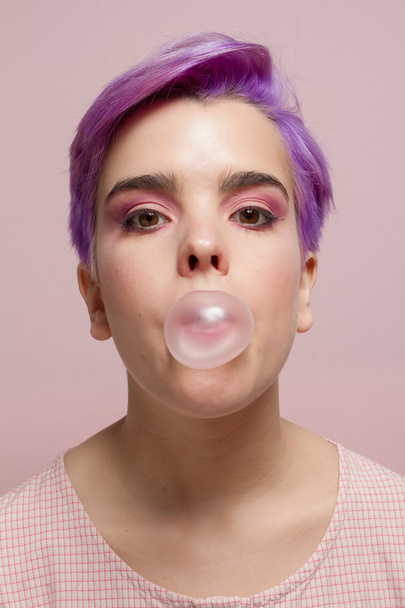 Violeta chica de pelo corto en pastel rosa, haciendo una burbuja rosa de
 - Foto, Imagen
