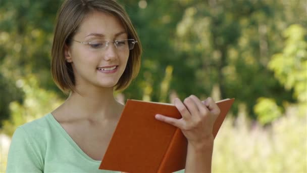 Young woman reading book with orange cover - 映像、動画
