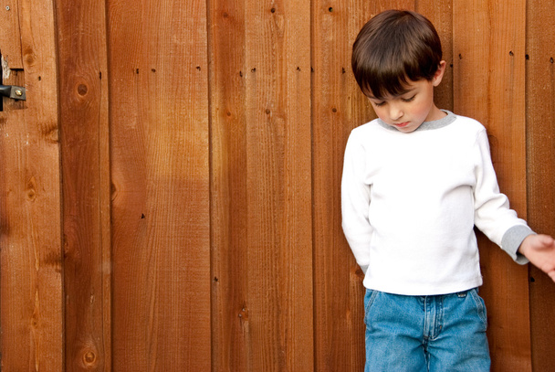 Νεαρό αγόρι, κοιτάζοντας προς τα κάτω σε ξύλινο φράχτη - Φωτογραφία, εικόνα