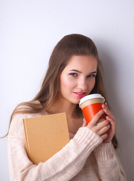 Portret młodej kobiety z filiżanką herbaty lub kawy, trzymając książkę - Zdjęcie, obraz